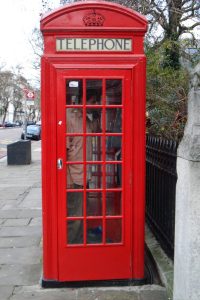 A red, British telephone box with a man inside.